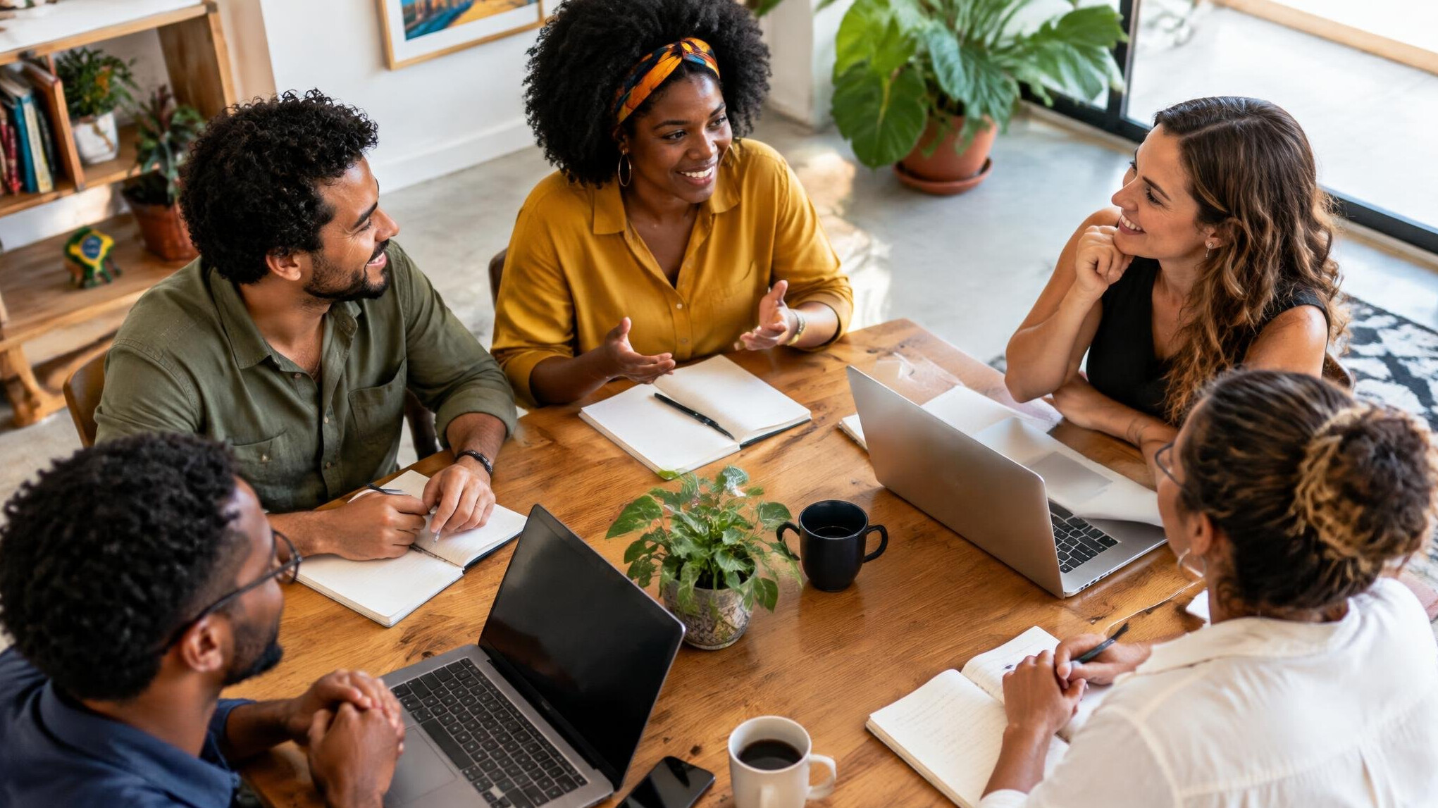 Group of people talking around a table with laptops and notebooks